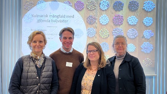 Fyra personer framför en bild på bönor