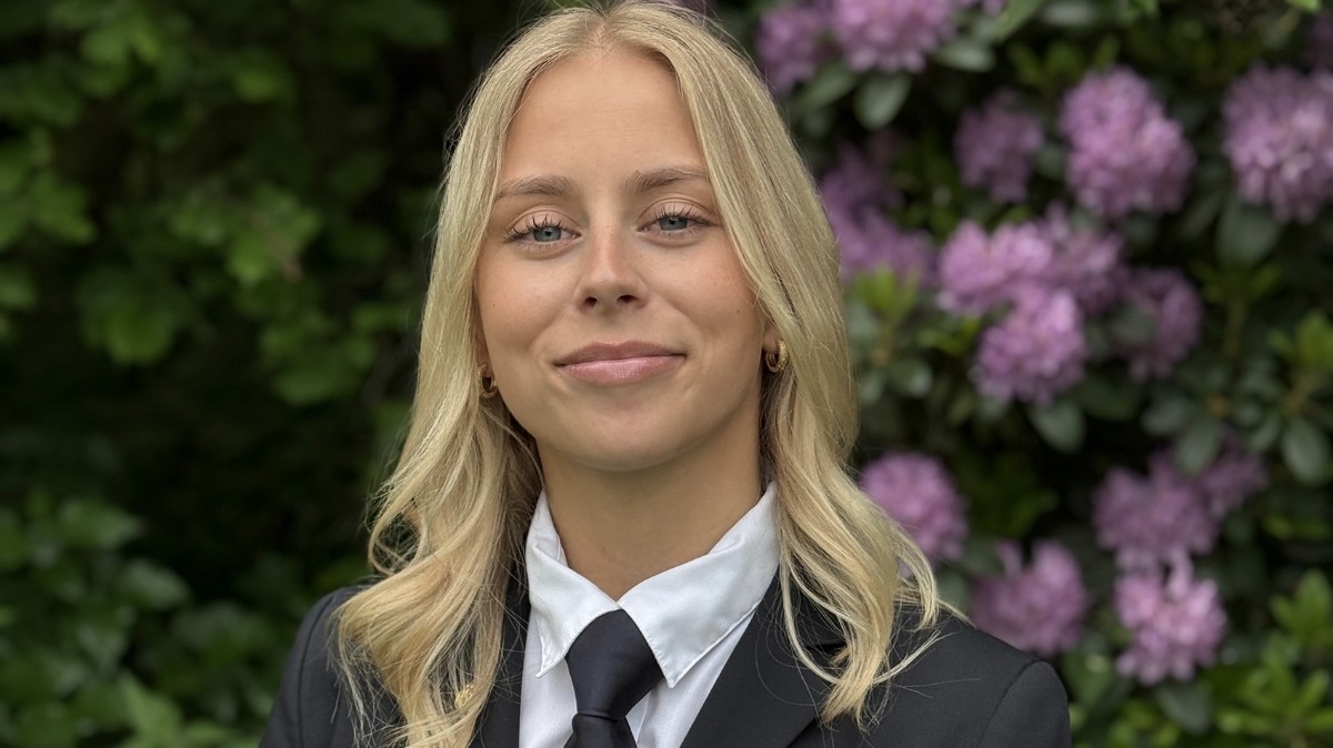 Kvinna med långt blont hår, vit skjorta och slips