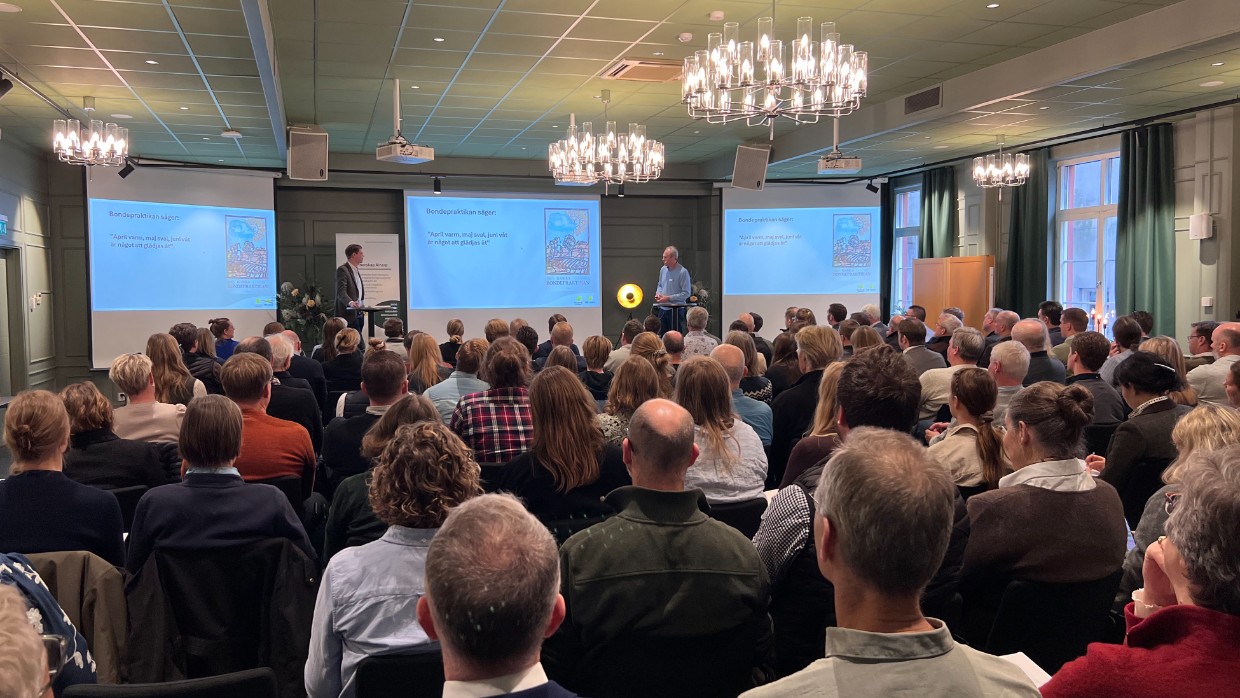 Två män föreläser för en stor grupp människor